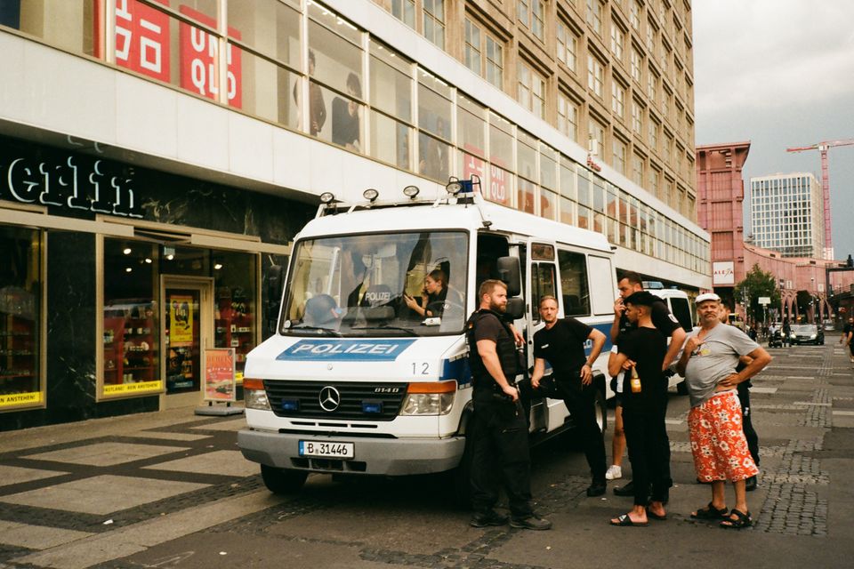 Absperrband und Blaulicht an einem abgesperrten Tatort mit einem Polizeifahrzeug.